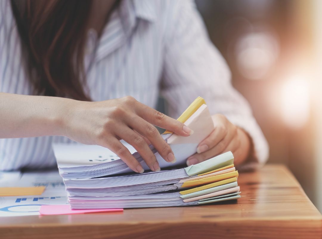 a person looking through organized stacks of paperwork