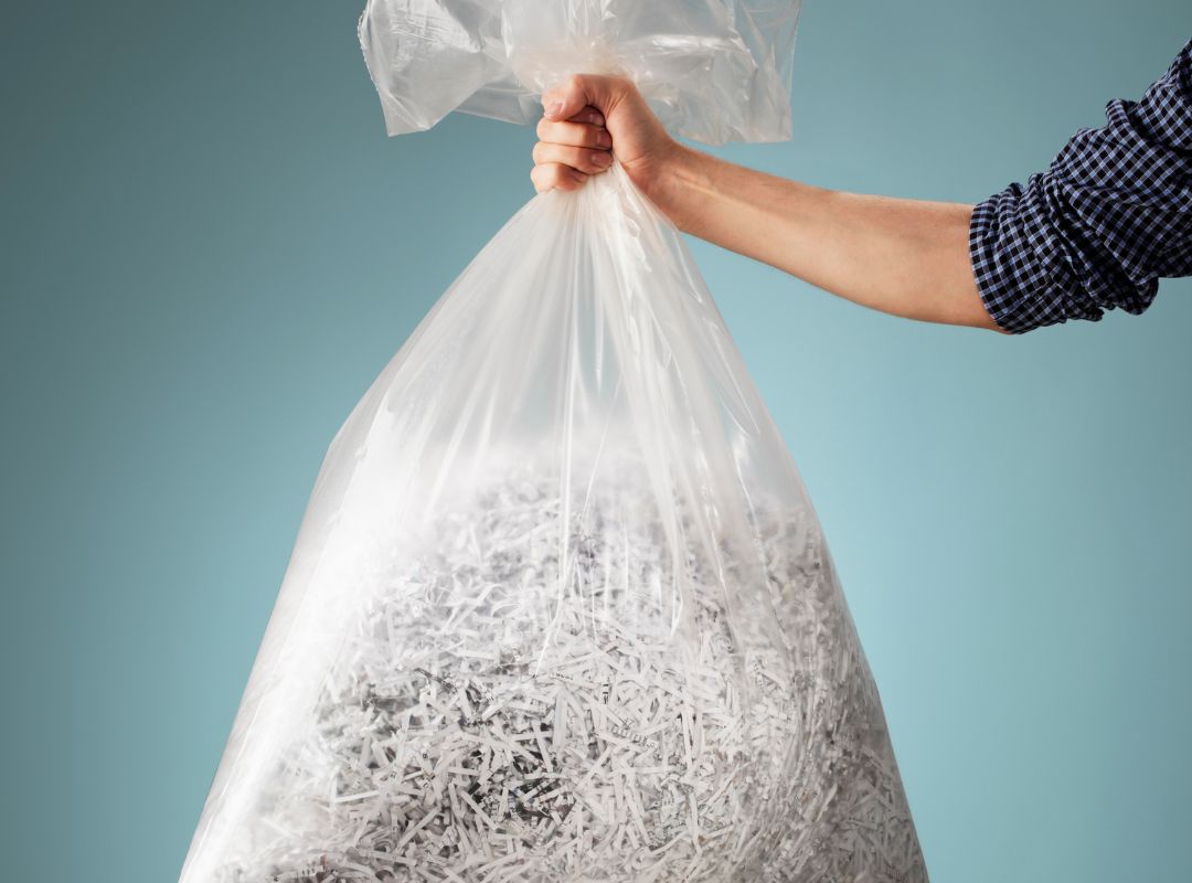 a person holding a large bag of shredded papers